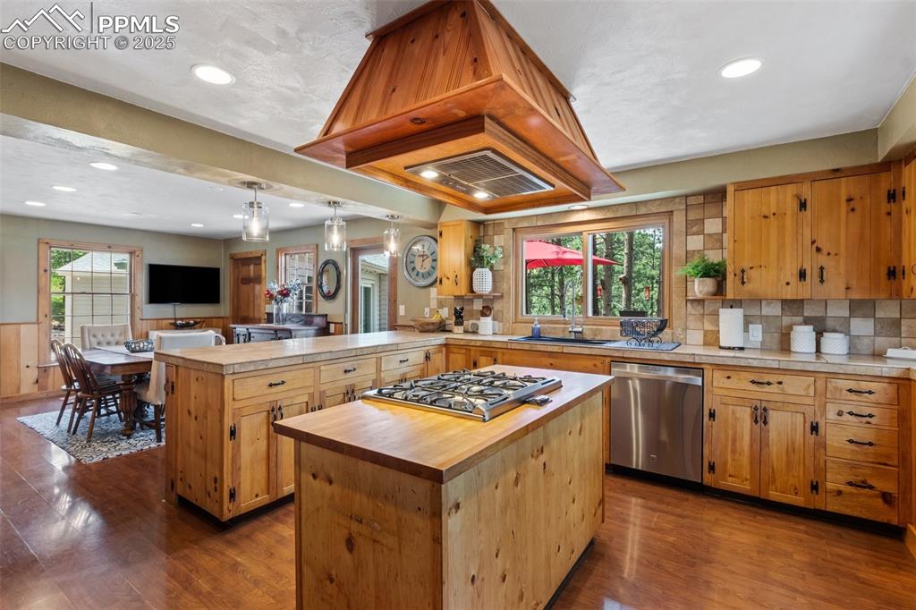 Image 19 of 50: Kitchen with stainless steel dishwasher, gas stovetop, a peninsula, a cente