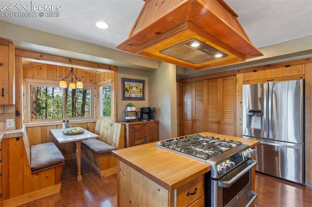 Image 20 of 50: Kitchen with stainless steel appliances, island range hood, butcher block c