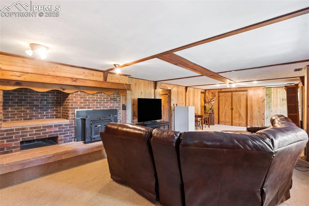 Image 39 of 50: Basement living area with wood walls and beam ceiling