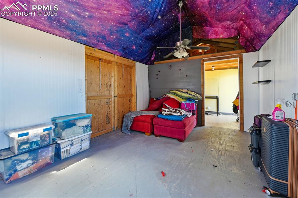 Image 14 of 48: Bedroom featuring a ceiling fan, concrete flooring, vaulted ceiling, and a 