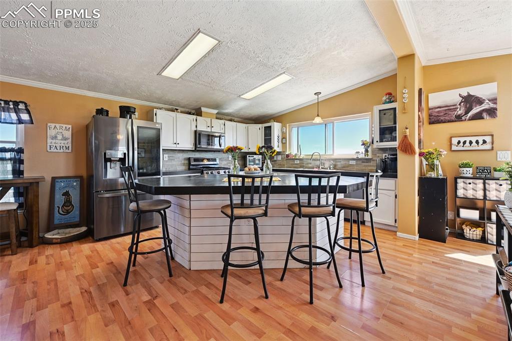 Image 21 of 48: Kitchen with tasteful backsplash, stainless steel appliances, white cabinet