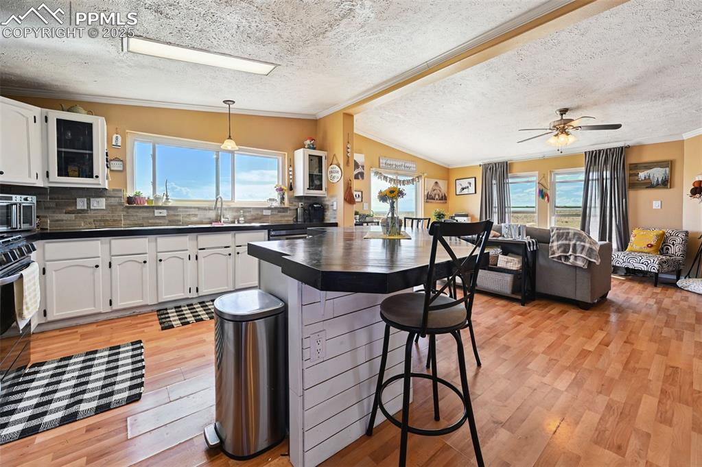 Image 22 of 48: Kitchen with crown molding, a breakfast bar area, dark countertops, white c