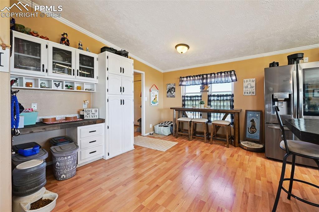 Image 24 of 48: Kitchen with white cabinets, a textured ceiling, stainless steel fridge, or