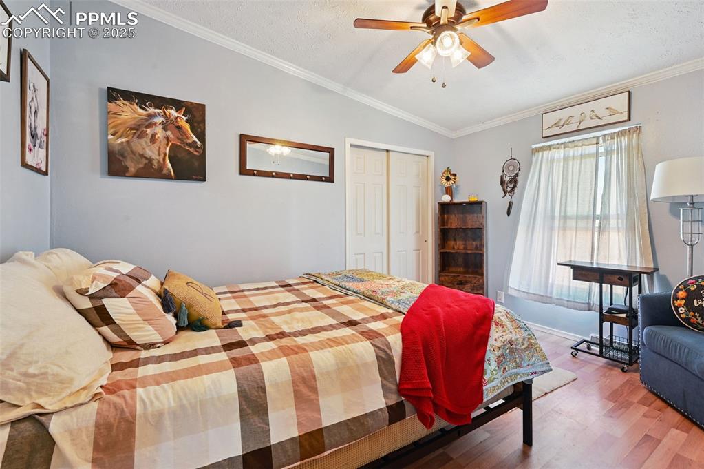 Image 36 of 48: Bedroom featuring wood finished floors, ornamental molding, vaulted ceiling