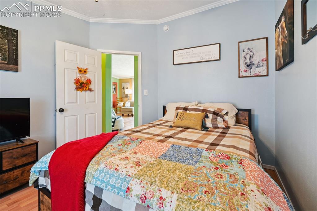 Image 37 of 48: Bedroom featuring ornamental molding and wood finished floors