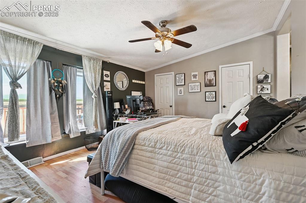 Image 38 of 48: Bedroom with a textured ceiling, wood finished floors, ornamental molding, 