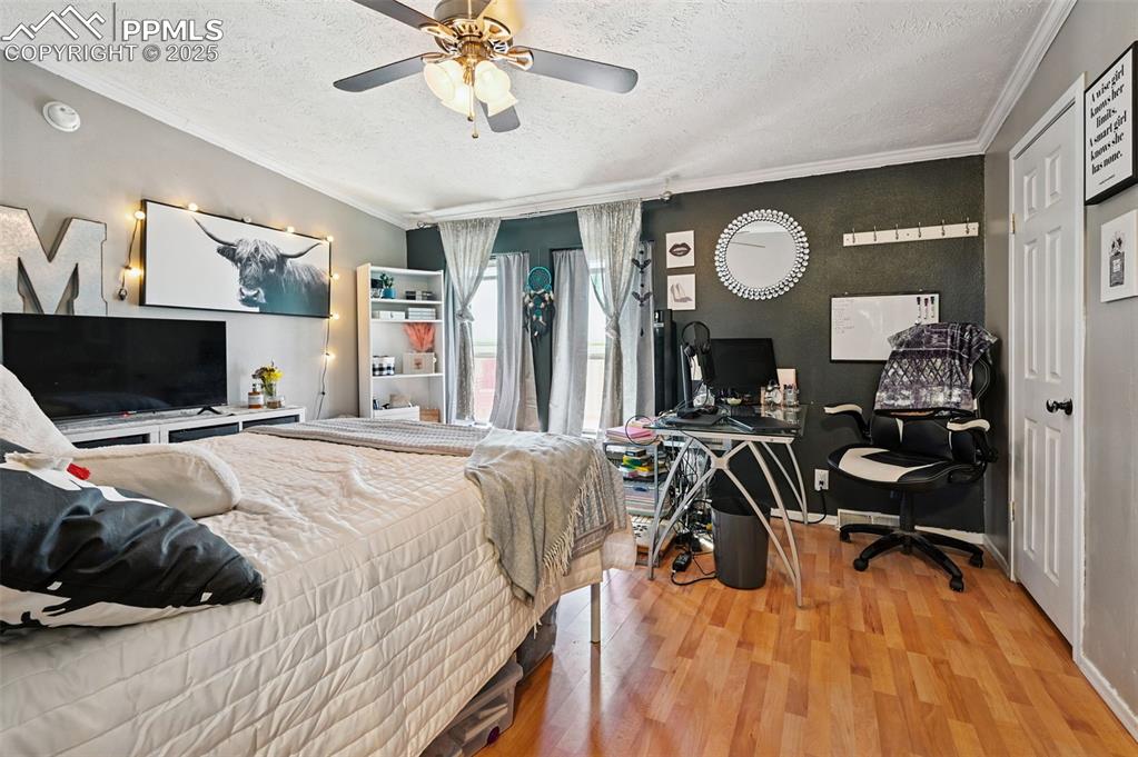 Image 41 of 48: Bedroom featuring a textured ceiling, crown molding, wood finished floors, 