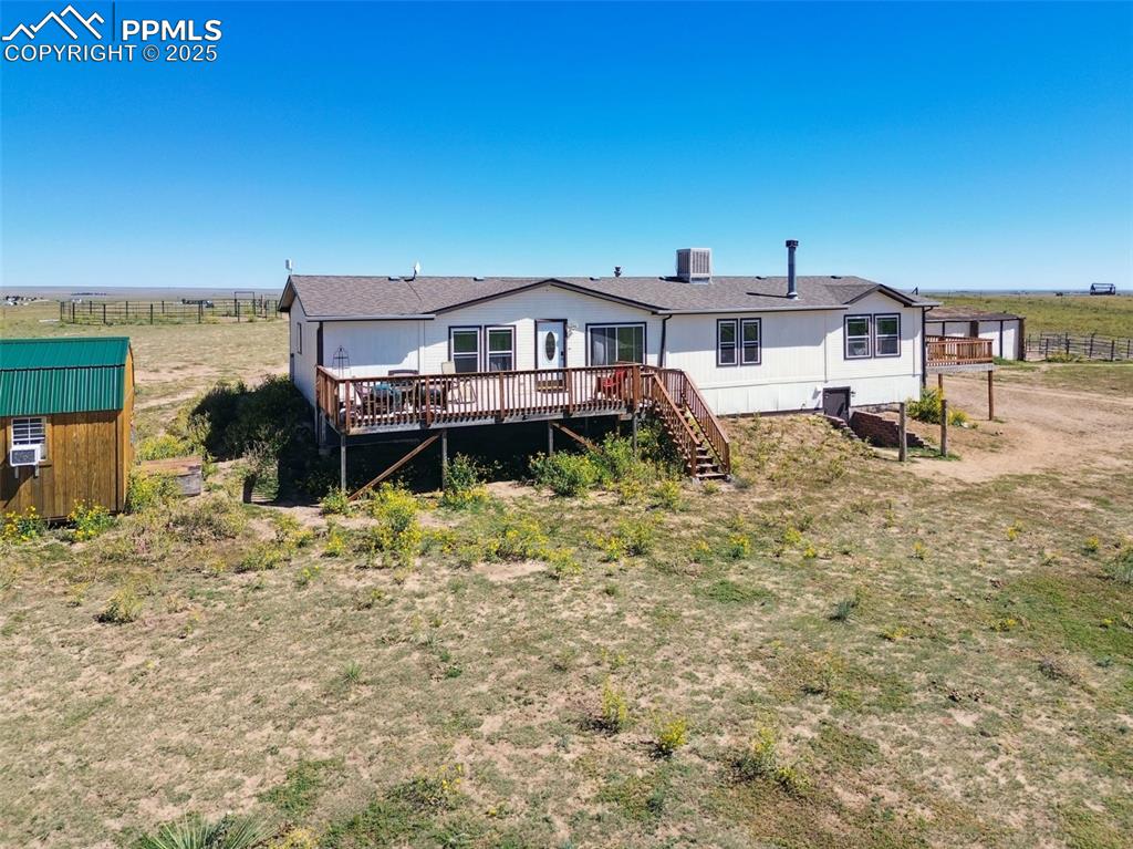 Image 6 of 48: Back of house featuring a deck, stairs, a view of countryside, and a storag