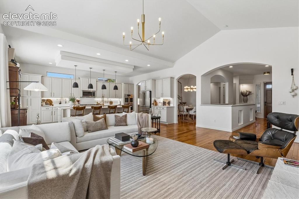 Image 10 of 50: Spacious living area featuring vaulted ceilings, wood-finish flooring, and