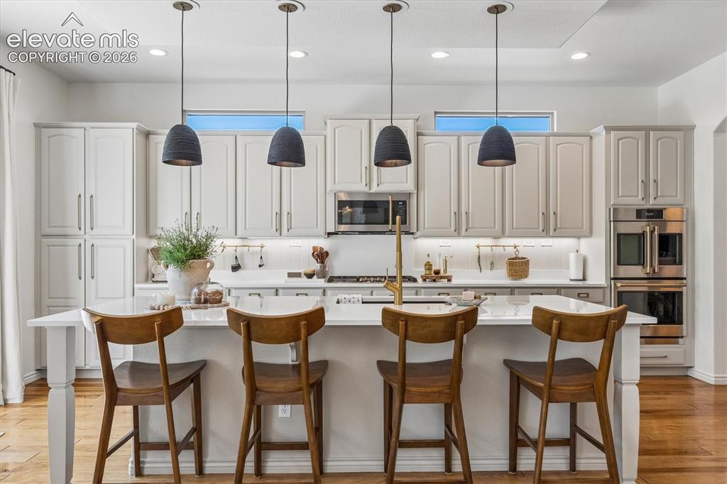 Image 11 of 50: Kitchen island with a white quartz countertop and modern pendant lights