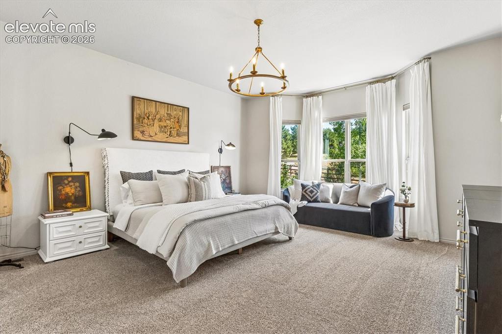 Image 18 of 50: Spacious primary suite featuring a sitting nook and a gold-finish chandelie