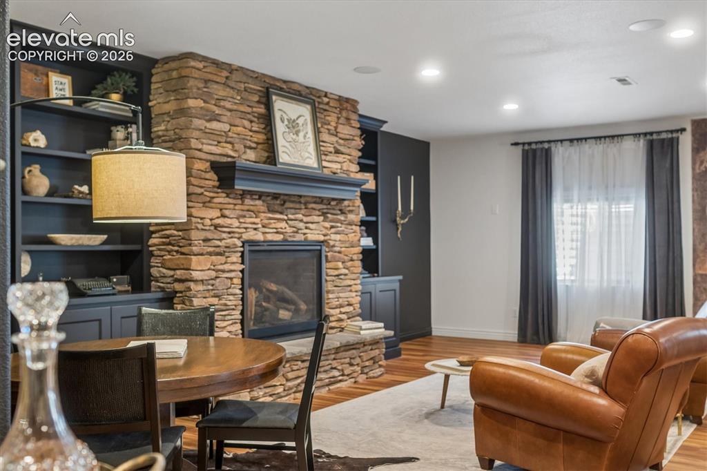 Image 26 of 50: Stone-clad fireplace with mantel and hearth, flanked by built-in shelving a