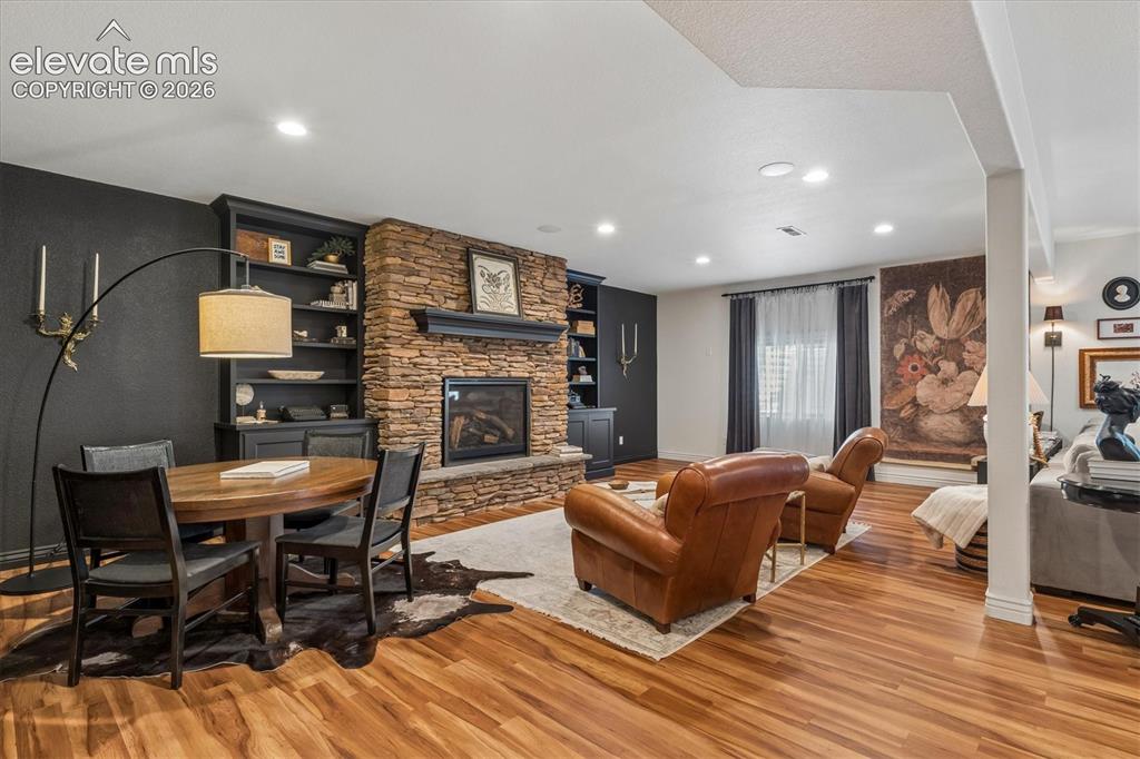 Image 28 of 50: Stone-clad fireplace with mantel, built-in shelving, wood-finish flooring,