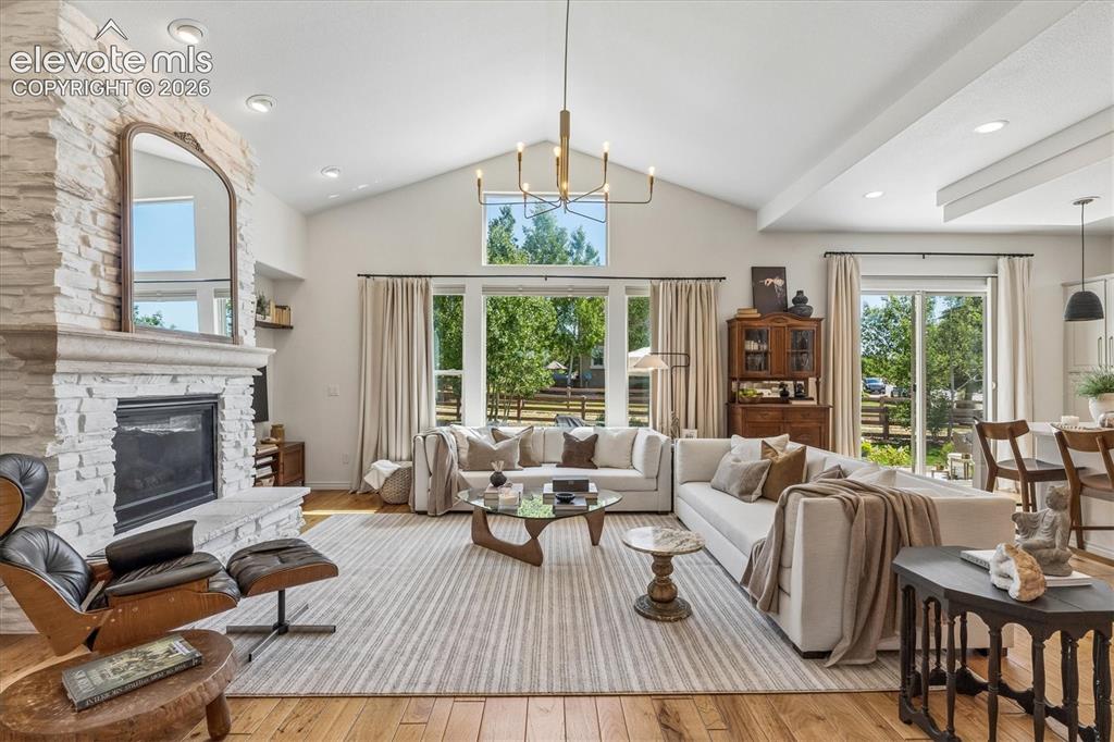 Image 3 of 50: Spacious living area featuring vaulted ceilings, wood-finish flooring, and