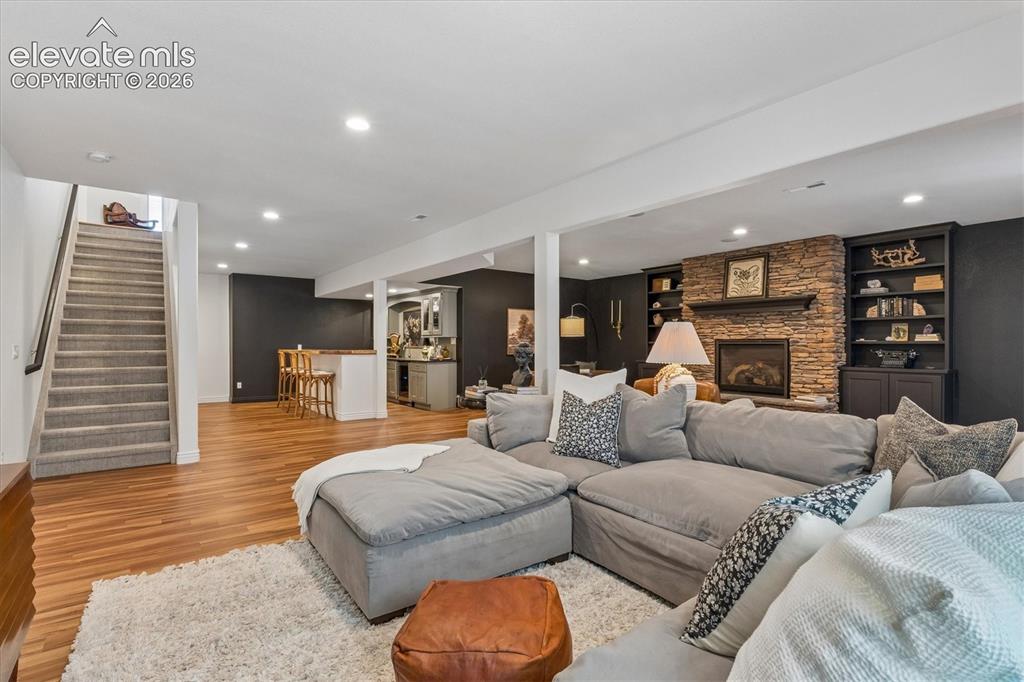 Image 32 of 50: Finished lower level featuring a stone-faced fireplace with a wood mantle,