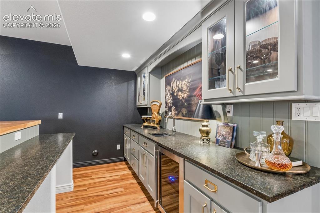 Image 33 of 50: Integrated wet bar featuring a beverage cooler, granite-finish countertops,