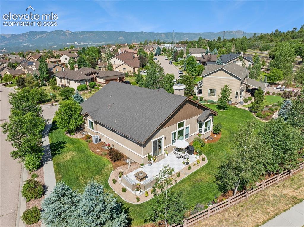 Image 45 of 50: Expansive backyard featuring a stone patio, mature trees, and landscaping