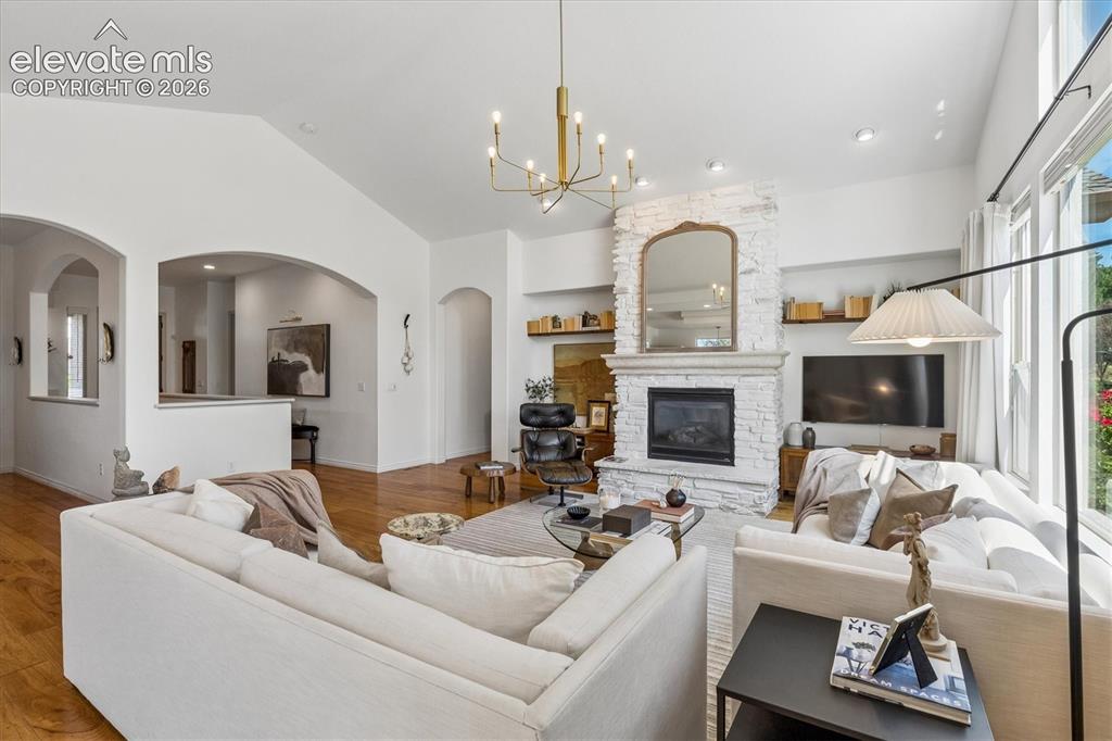 Image 5 of 50: Living area featuring vaulted ceilings and a stone-clad fireplace.