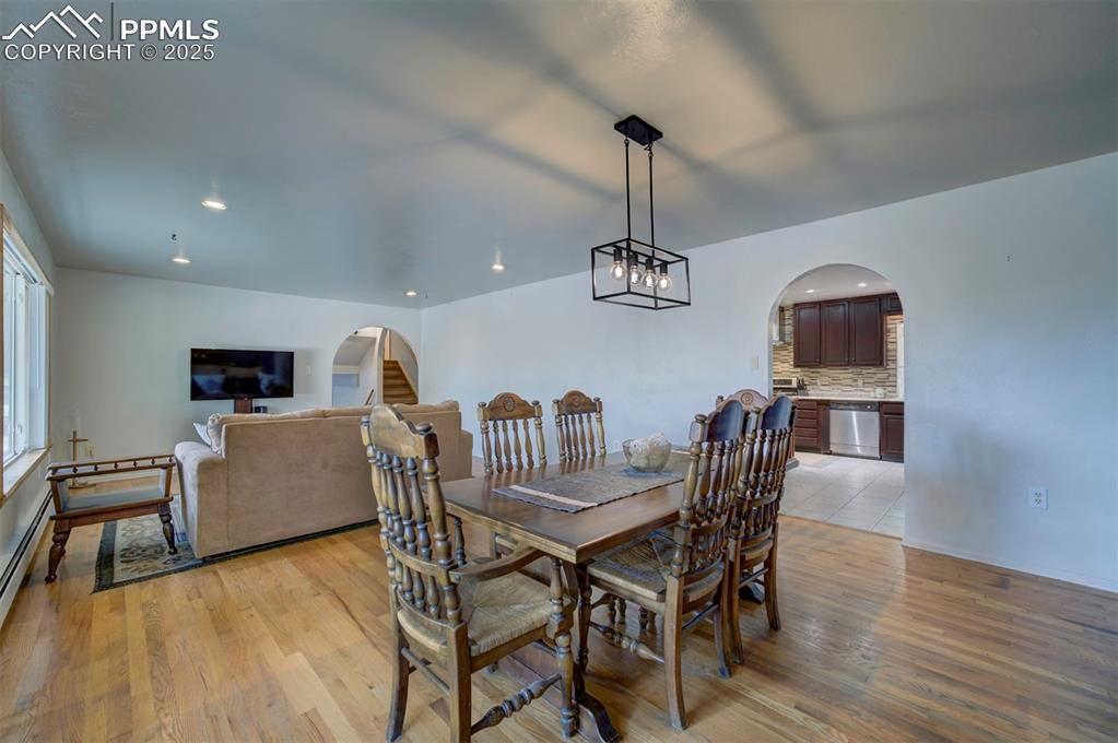 Image 10 of 44: Dining room featuring arched walkways, a chandelier, light wood-style floor