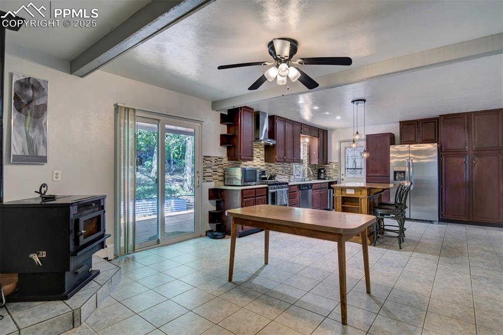 Image 12 of 44: Kitchen with a wood stove, backsplash, stainless steel appliances, beam cei