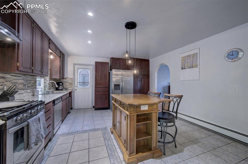 Image 16 of 44: Kitchen with light tile patterned flooring, decorative backsplash, wall chi