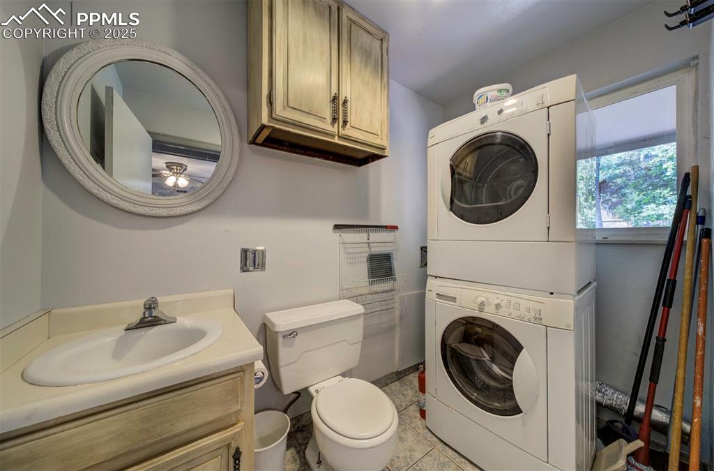 Image 17 of 44: Bathroom featuring vanity, stacked washer and clothes dryer, and light tile