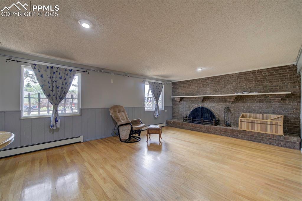 Image 18 of 44: Living area with a textured ceiling, a wainscoted wall, rail lighting, wood
