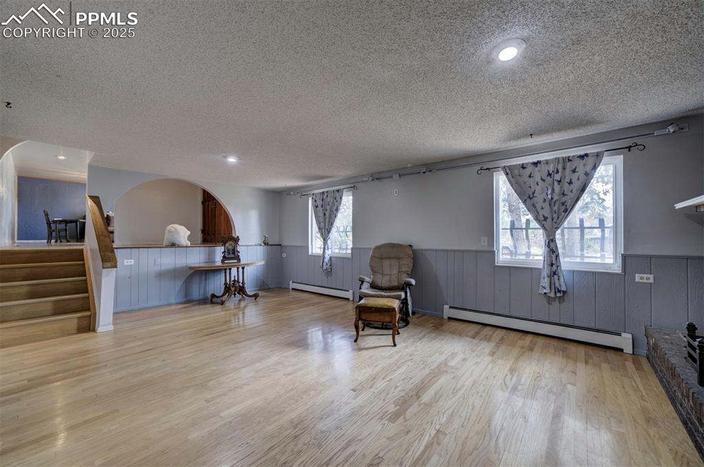 Image 19 of 44: Living area featuring a wainscoted wall, a baseboard heating unit, light wo