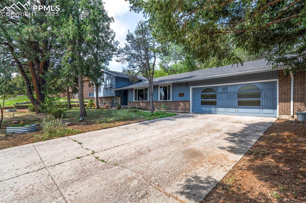Image 2 of 44: Split level home with brick siding, driveway, and a shingled roof