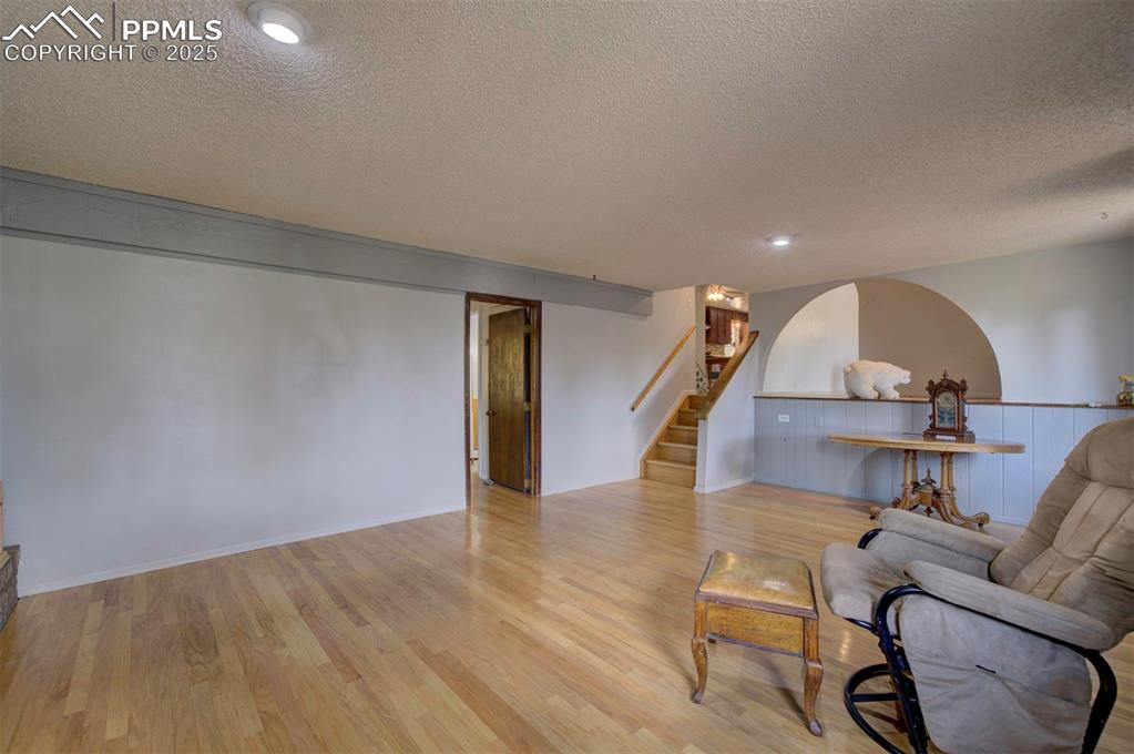 Image 20 of 44: Living area featuring stairway, a textured ceiling, and light wood-style fl