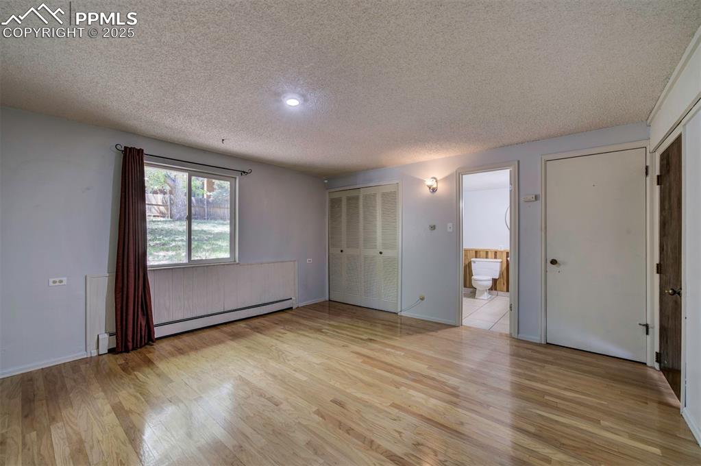 Image 23 of 44: Unfurnished bedroom with light wood finished floors, a textured ceiling, co