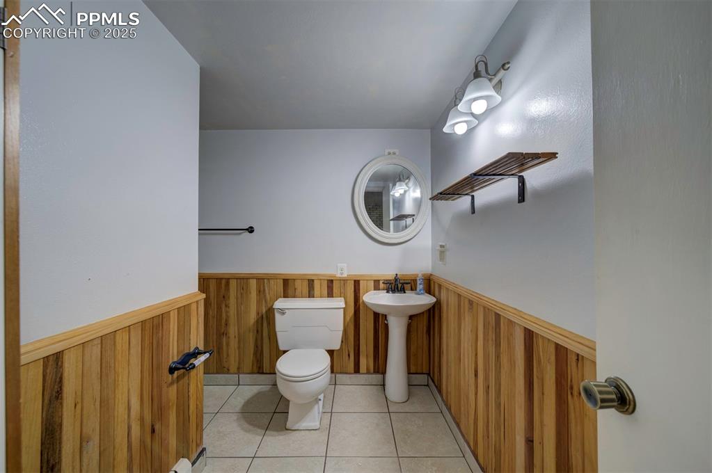 Image 24 of 44: Bathroom featuring light tile patterned flooring, wood walls, and wainscoti