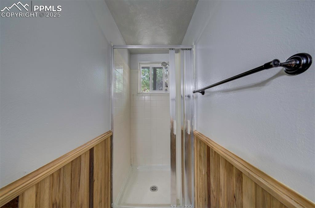 Image 25 of 44: Full bath featuring a wainscoted wall and a stall shower