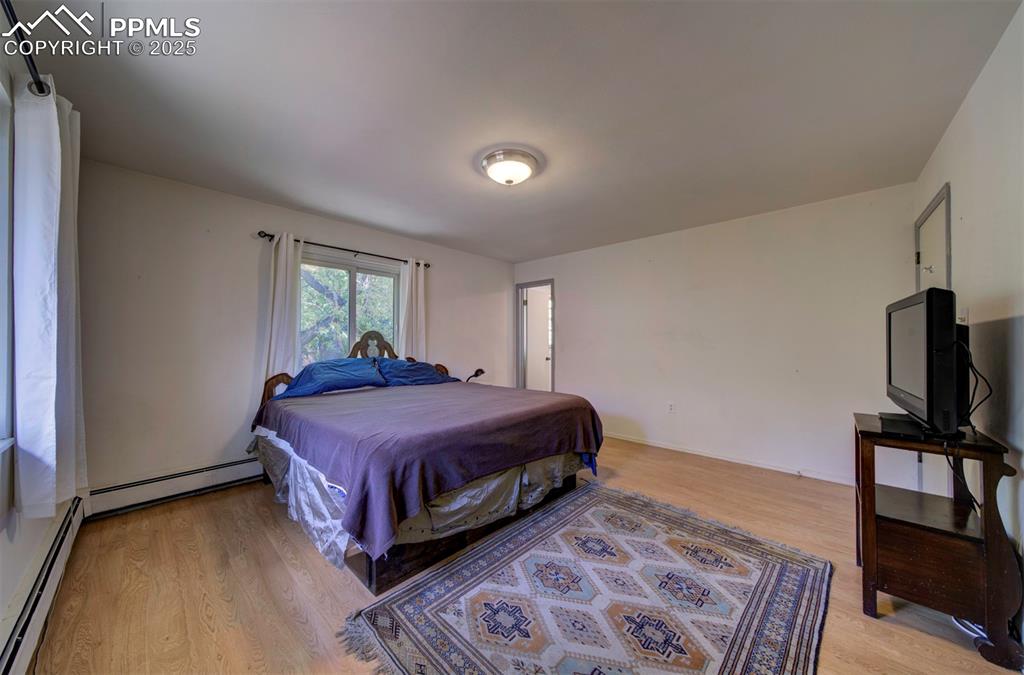 Image 26 of 44: Bedroom with a baseboard heating unit, light wood-style floors, and baseboa