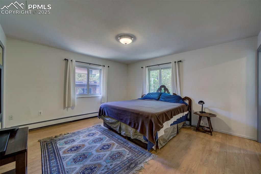 Image 27 of 44: Bedroom with light wood-type flooring, multiple windows, and a baseboard he