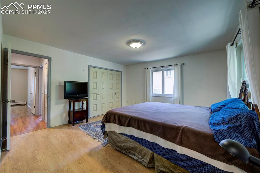 Image 28 of 44: Bedroom with light wood-style floors, baseboard heating, and a closet