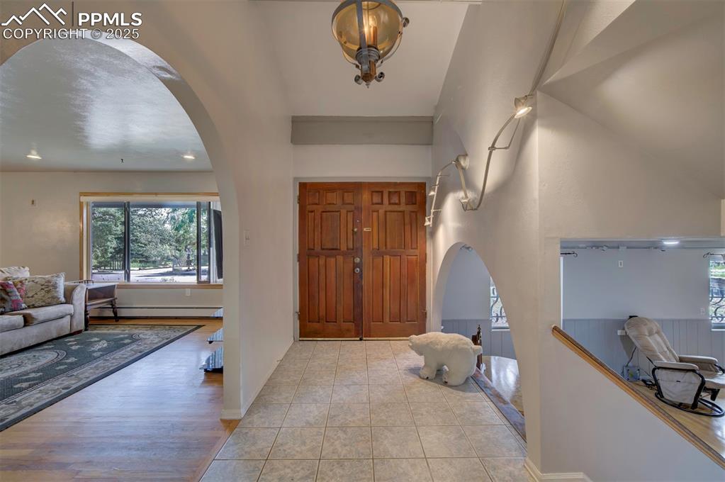 Image 3 of 44: Tiled entrance foyer with arched walkways and a baseboard radiator
