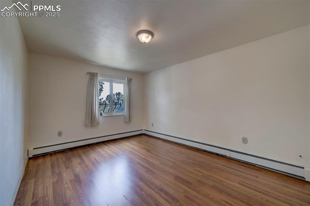 Image 31 of 44: Empty room featuring light wood-type flooring and baseboard heating