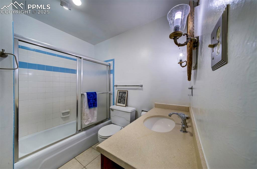 Image 34 of 44: Full bath featuring enclosed tub / shower combo, vanity, and light tile pat