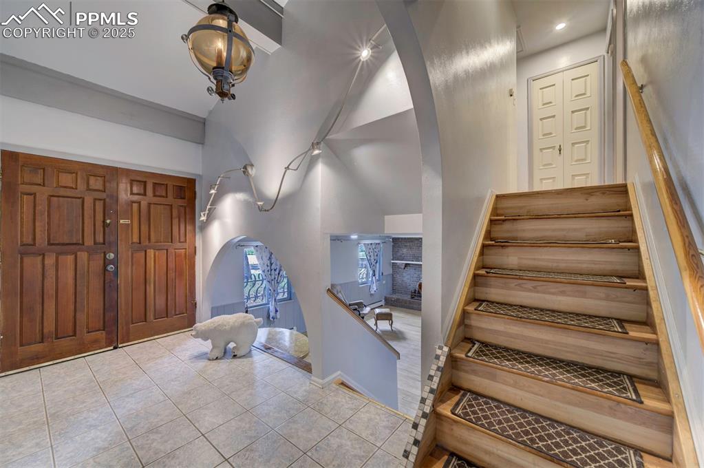 Image 4 of 44: Foyer entrance featuring arched walkways, stairway, high vaulted ceiling, a