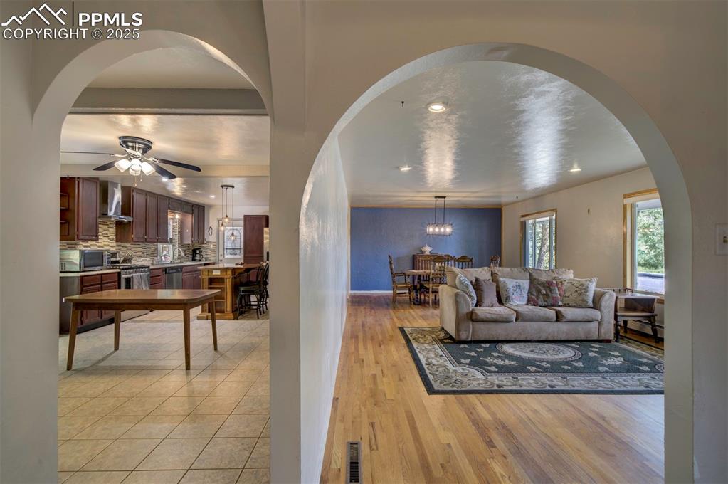Image 6 of 44: Living room with arched walkways, a ceiling fan, light wood-type flooring,