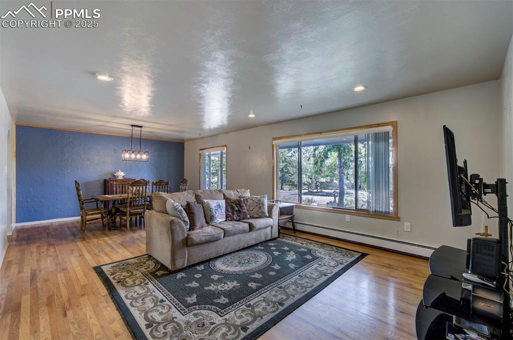 Image 7 of 44: Living room with a textured wall, a baseboard heating unit, light wood-styl