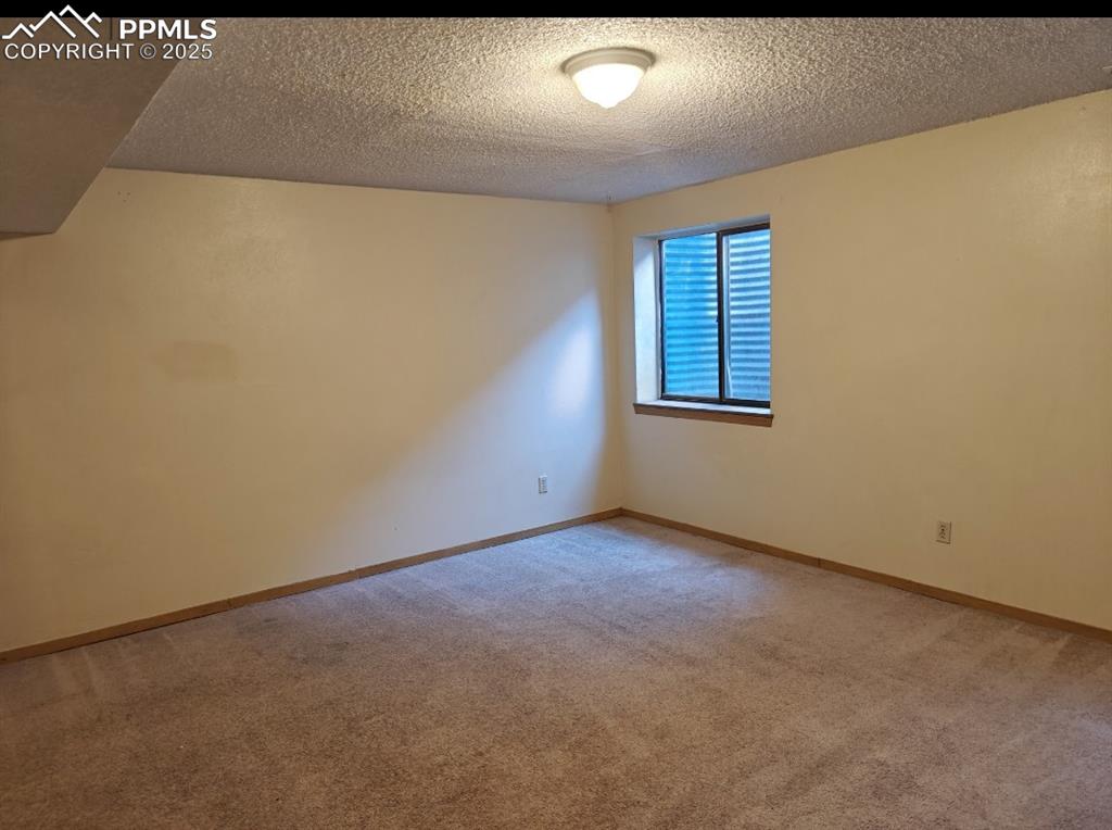 Image 12 of 17: Empty room with light colored carpet and a textured ceiling