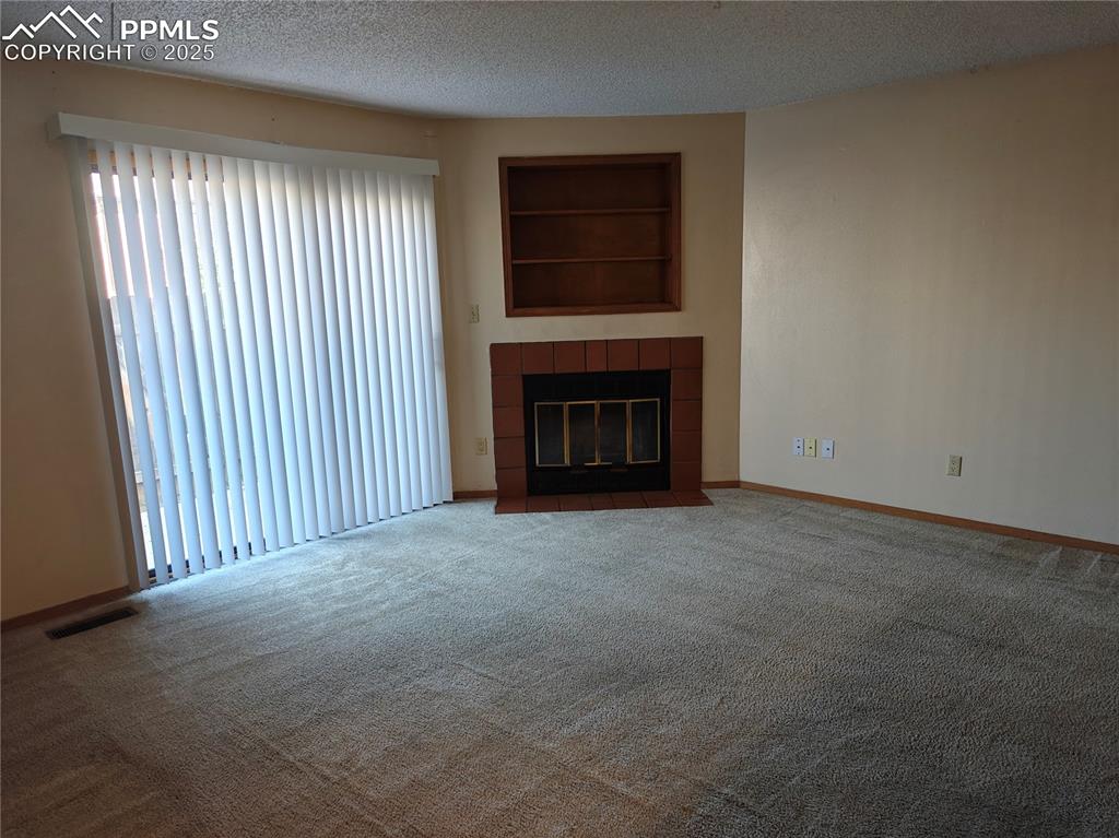 Image 3 of 17: Unfurnished living room featuring carpet flooring, a textured ceiling, a ti