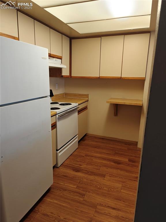 Image 6 of 17: Kitchen featuring white appliances, wood finished floors, light countertops