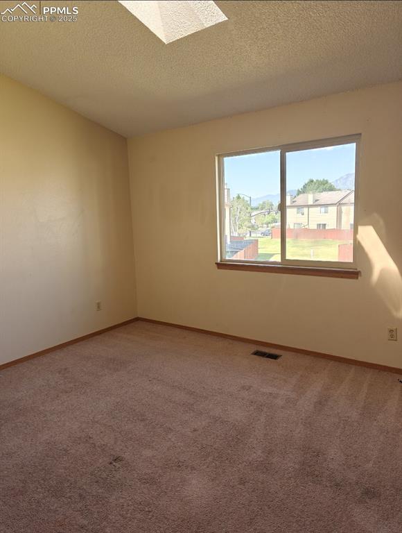 Image 9 of 17: Carpeted empty room featuring a textured ceiling and a skylight