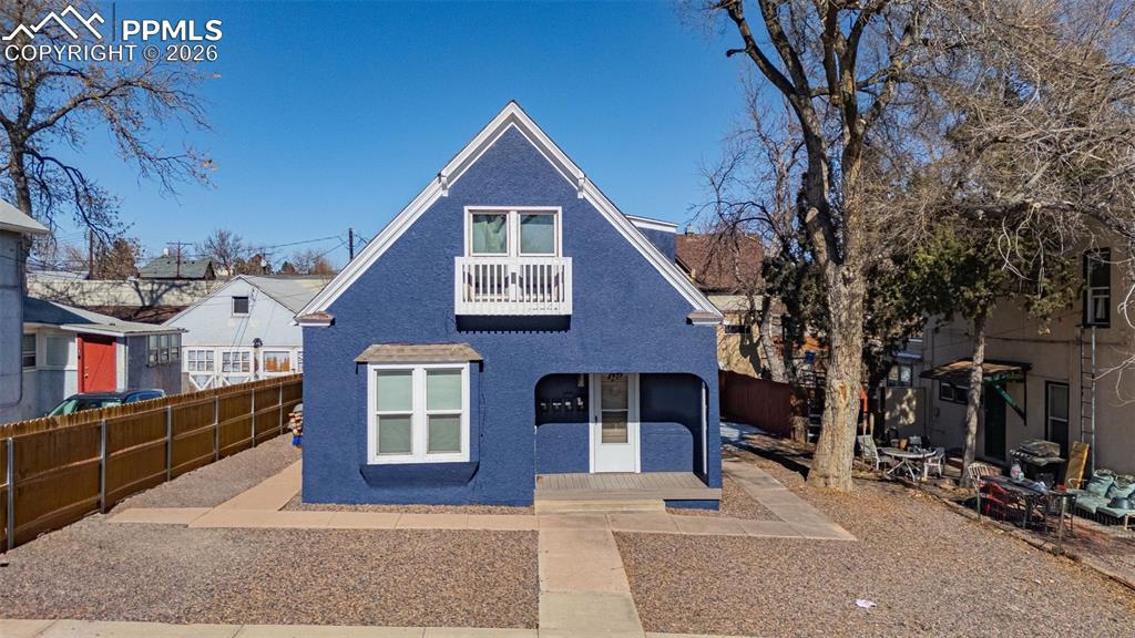 Caption: View of front facade featuring a patio area, a fenced backyard, a balcony, and stucco siding
