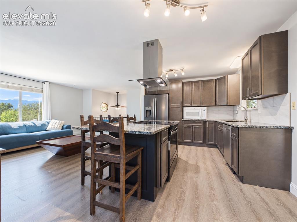 Image 10 of 50: Updated kitchen with dark cabinetry, granite-style countertops, stainless s