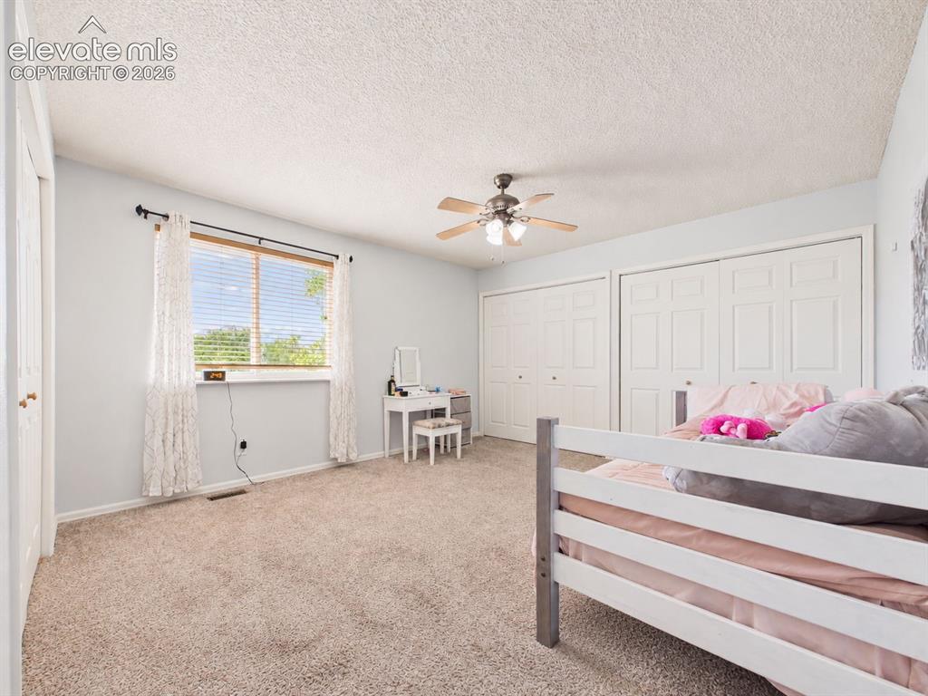 Image 23 of 50: Bright secondary bedroom features a large window, ceiling fan, neutral fini