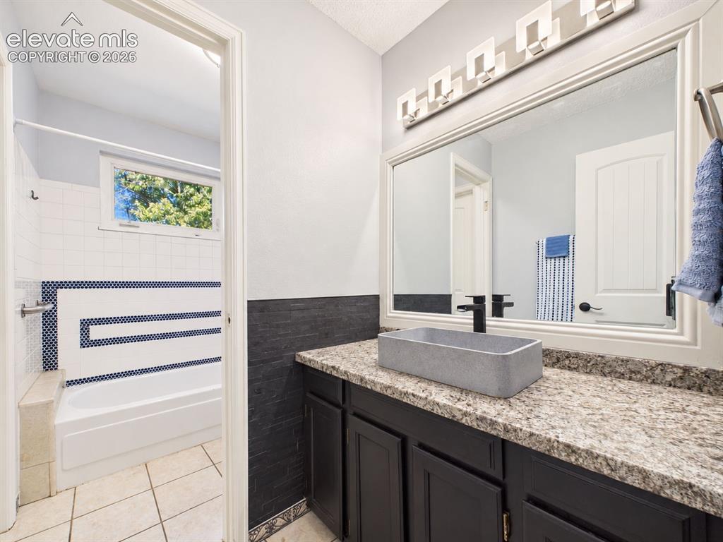 Image 27 of 50: Bathroom vanity pairs dark cabinetry with a stone-look countertop, rectangu